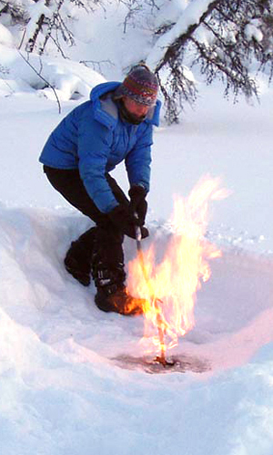 AF researcher Katey Walter lights a pocket of methane on a thermokarst lake in Siberia in March of 2007. Igniting the gas is a way to demonstrate, in the field, that it contains methane